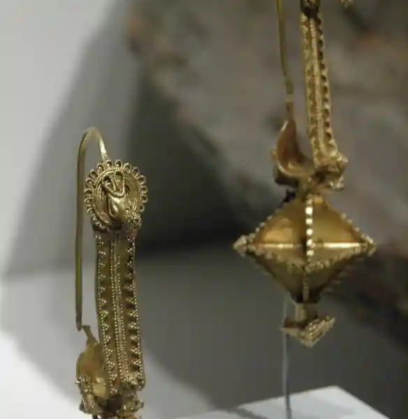 Gold earrings with a diamond pendant that looks like a 3D cross